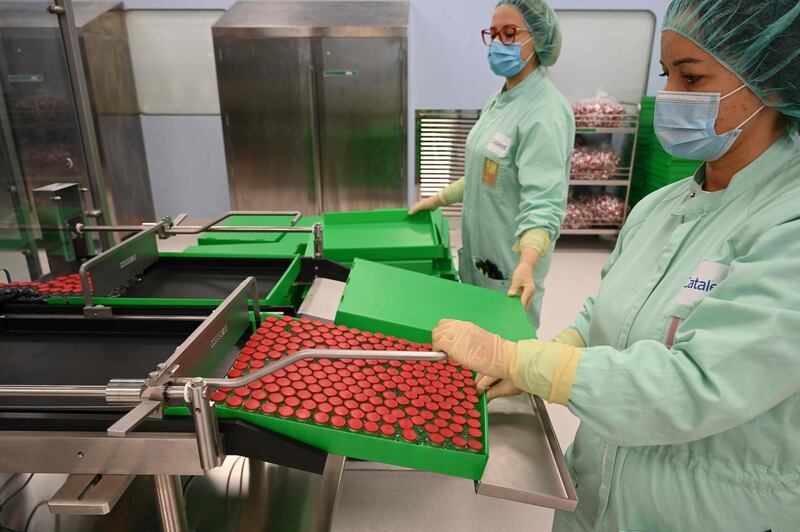 Laboratory technicians handles capped vials as part of filling and packaging tests for the large-scale production and supply of the University of Oxford’s COVID-19 vaccine candidate, AZD1222, conducted on a high-performance aseptic vial filling line on September 11, 2020 at the Italian biologics’ manufacturing facility of multinational corporation Catalent in Anagni, southeast of Rome, during the COVID-19 infection, caused by the novel coronavirus.  Catalent Biologics’ manufacturing facility in Anagni, Italy will serve as the launch facility for the large-scale production and supply of the University of Oxford’s Covid-19 vaccine candidate, AZD1222, providing large-scale vial filling and packaging to British-Swedish multinational pharmaceutical and biopharmaceutical company AstraZeneca. / AFP / Vincenzo PINTO                      
