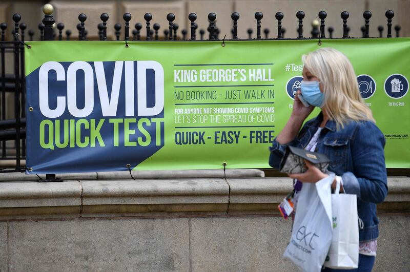A pedestrian wearing a face covering walks past a sign for a walk-in Covid-19 testing centre in Blackburn, north west England on June 16, 2021. The UK government on Monday announced a four-week delay to the full lifting of coronavirus restrictions in England due to a surge in infections caused by Delta, which first appeared in India. / AFP / Oli SCARFF
