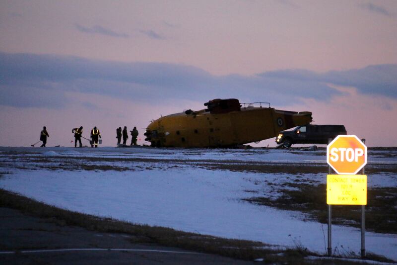 Emergency crews work around the wreckage of a downed CH-149 Cormorant search and rescue helicopter in Gander, Newfoundland and Labrador.  The Royal Canadian Air Force said there were six crew members on board.  AP Photo