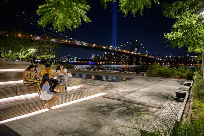 People sit in front of the 'Tribute in Light' installation in New York, commemorating the 9/11 terrorist attacks. AFP