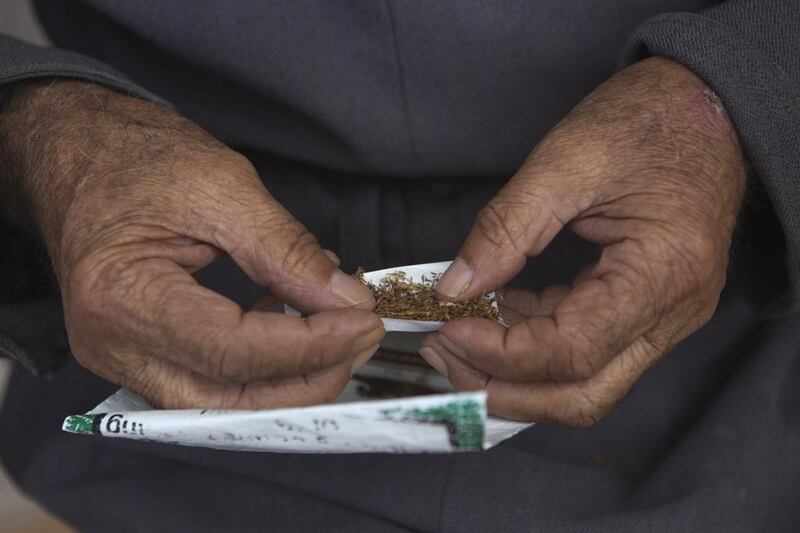 Hussein Atatarah, the patriarch of the family as he rolls a cigarette with the tobacco the family produces  in the Palestinian village of Zbouba near the city of Jenin on August 24,2015. All generations in the family help and work in the family’s cottage tobacco industry helping  to produce their final product ,cigarettes .