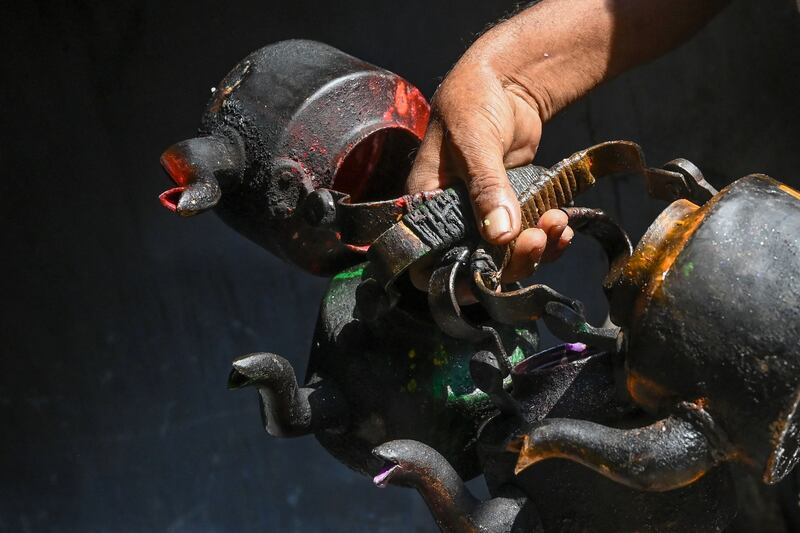 A worker at a candle-making facility carries kettles to heat paraffin to make coloured candles in Kolkata. AFP