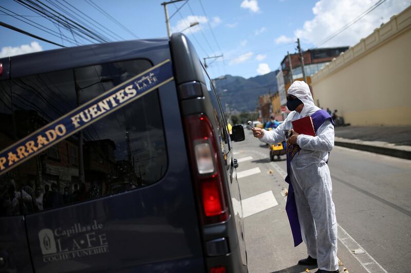 Victor Nieto, a Catholic deacon of the Capillas de la Fe funeral home, conducts a farewell ceremony for Jose Parrado, who died from Covid-19, outside Chapinero cemetery in Bogota, Colombia. Reuters