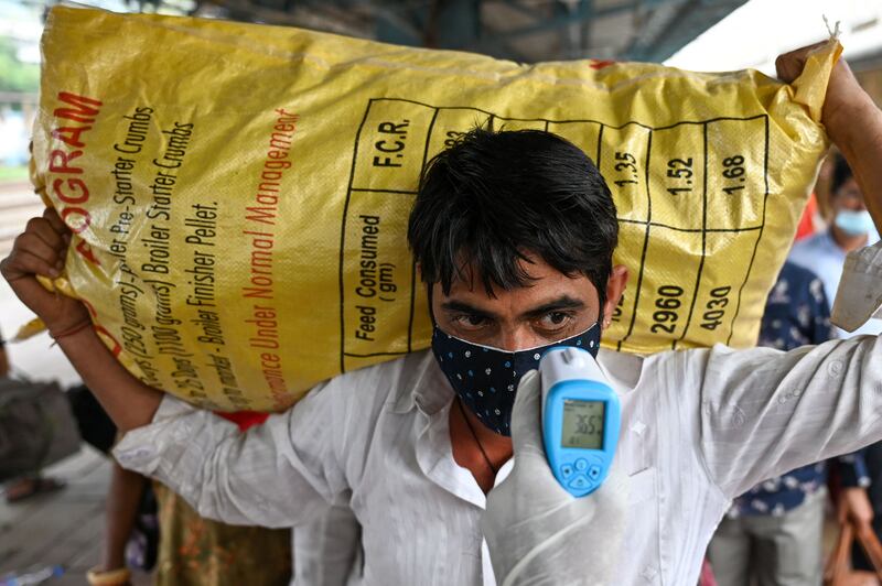 Even those carrying heavy bags have to have their temperatures checked, in Mumbai.  AFP