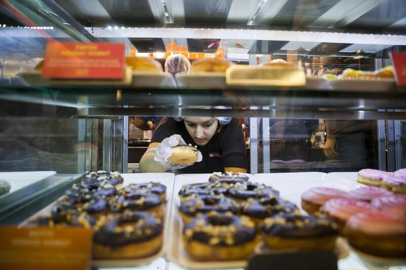 An employee takes a donut from a display cabinet at a Dunkin' Donuts store in New Delhi, India. Prashanth Vishwanathan / Bloomberg News