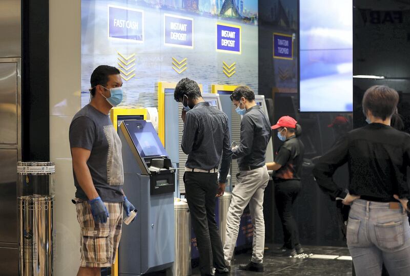 DUBAI, UNITED ARAB EMIRATES , April 29 – 2020 :- People using ATM at the Emirates NBD bank and wearing protective face mask and gloves to prevent the spread of the coronavirus at Mall of the Emirates in Dubai. Authorities ease the restriction for the residents in Dubai. At present mall opening timing is 12:00 pm to 10:00 pm. Carrefour timing is 9:00 am to 10:00 pm. (Pawan Singh / The National) For News/Standalone/Online. Story by Patrick