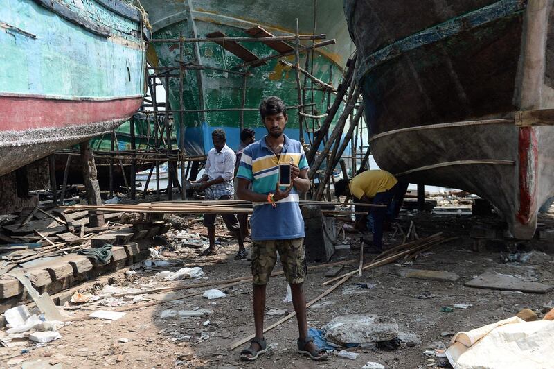 (FILES) In this file photo taken on November 9, 2018 Indian carpenter Deepan Raj, 25, poses with his smartphone at a fishing vessel dockyard at Kasimedu harbour in Chennai. / AFP / ARUN SANKAR
