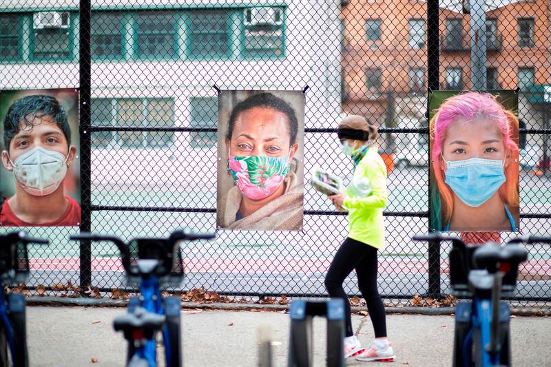 A woman walks past pictures made by AJ Stetson, part of his "Masked NYC" exhibition, on the Upper West Side area of Manhattan New York.  AFP