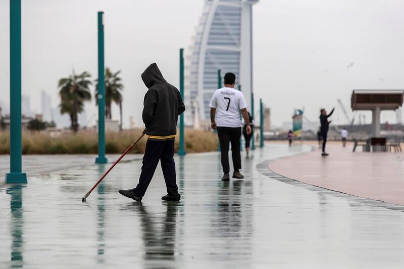 DUBAI, UNITED ARAB EMIRATES. 10 JANUARY 2020. Heavy rains in Dubai during the night had residenst wake up to wet pavements and large water puddles with some areas experiencng mild flooding. A man sweeps water on from the running track along Kite Beach. (Photo: Antonie Robertson/The National) Journalist: Standalone. Section: National.

