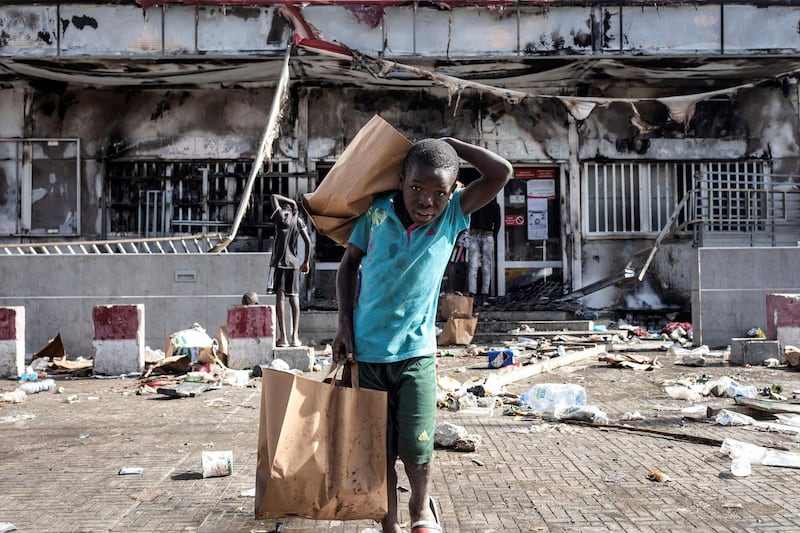 A young boy holds grocery bags as he walks away from a supermarket which was burnt down and looted in the upmarket area of Almadies in Dakar, Senegal. Protests have been ongoing for three days in the country after opposition leader Ousmane Sonko was arrested following rape charges. The Senegal government vowed to use "all means necessary" to return order after police fired tear gas in clashes with supporters of opposition leader Ousmane Sonko. AFP