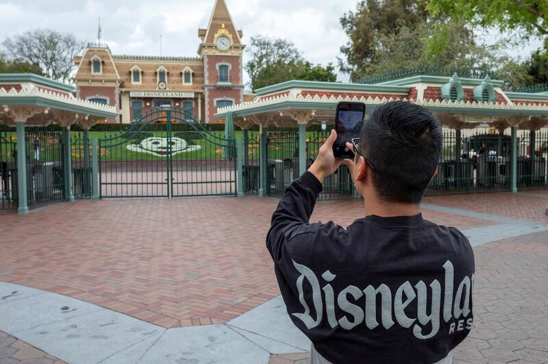 A man takes a photo outside the gates of Disneyland Park on the first day of the closure of Disneyland and Disney California Adventure theme parks as fear of the spread of coronavirus continue, in Anaheim, California, on March 14, 2020. - The World Health Organization said March 13, 2020 it was not yet possible to say when the COVID-19 pandemic, which has killed more than 5,000 people worldwide, will peak. "It's impossible for us to say when this will peak globally," Maria Van Kerkhove, who heads the WHO's emerging diseases unit, told a virtual press conference, adding that "we hope that it is sooner rather than later". (Photo by DAVID MCNEW / AFP)