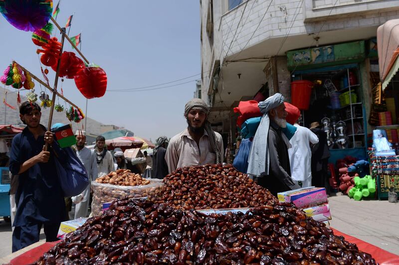 An Afghan date vendor (C) waits for customers ahead of the Islamic holy month of Ramadan in Kabul on July 7, 2013.  Throughout the month, devout Muslims must abstain from food and drink from dawn until sunset when they break the fast with the Iftar meal. Traditionally, dates are known as the food the prophet Mohammad ate when he broke from his fast.  AFP PHOTO / Massoud HOSSAINI
 *** Local Caption ***  507100-01-08.jpg