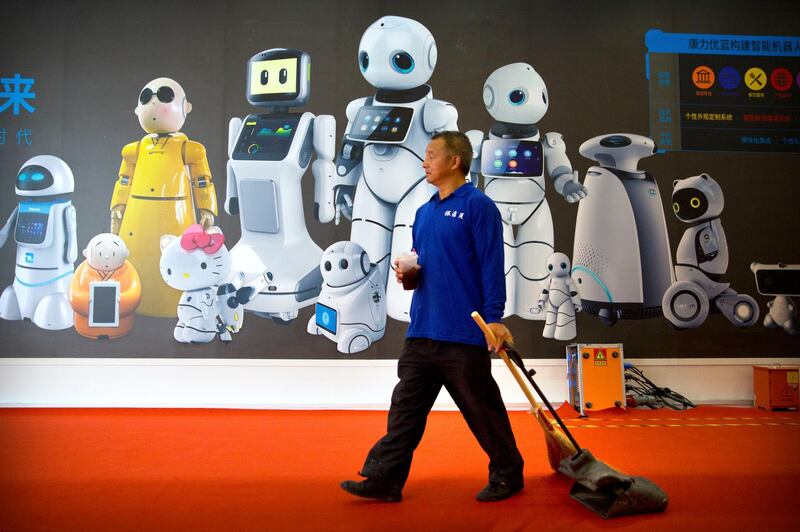 A maintenance worker walks past a mural displaying robots from Chinese robot maker Canbot at the World Robot Conference in Beijing. AP Photo