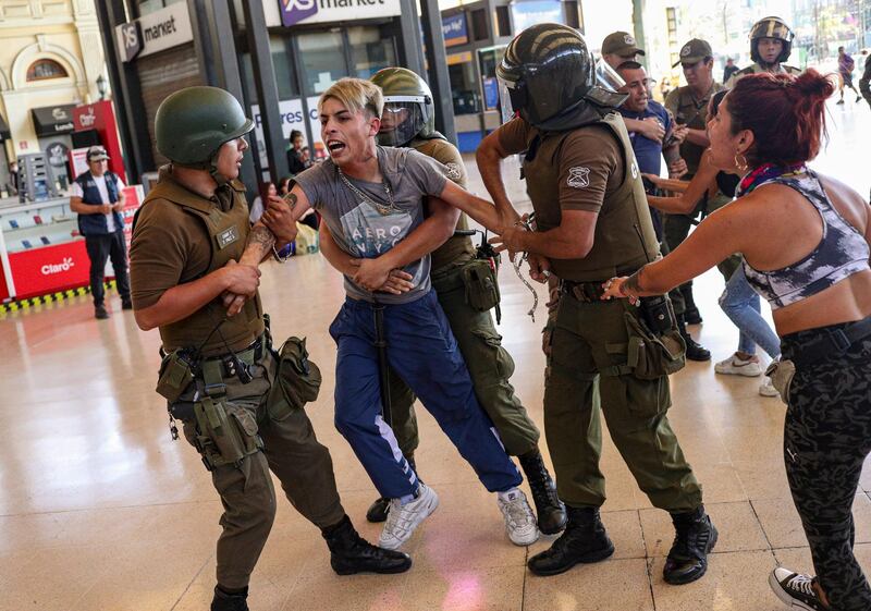 Police detain two street vendors to evict them from the train station in Santiago, Chile. AP Photo