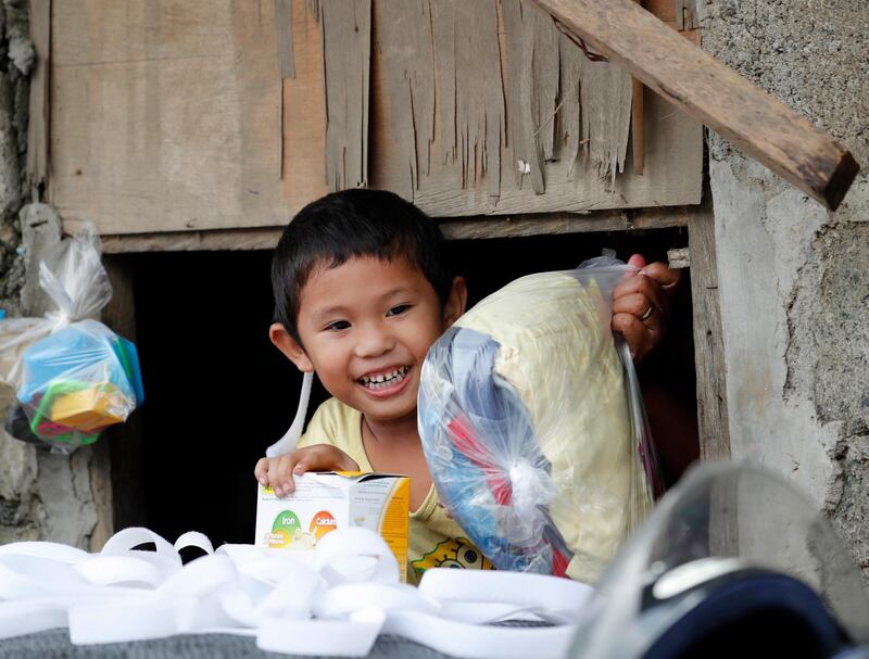 A Filipino boy receives a bag of goods from motorcycle riders during a relief operation in flood-hit city Marikina. EPA