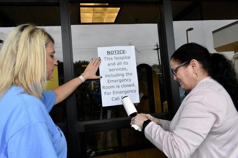 Carol Talkington helps Terri Bonasso tape a notice on the emergency room door following a vigil at the closing of the Fairmont Regional Medical Centre in Fairmont. Times-West Virginian via AP