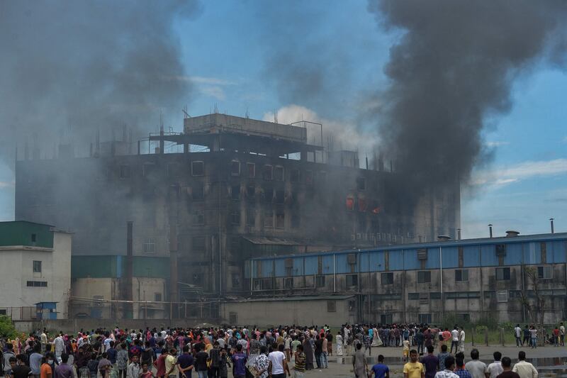 Onlookers watch as smoke bellows from a massive fire that broke out a day before in a beverage and food factory in Rupganj in the district Narayanganj, that has reportedly claimed 43 lives so far.