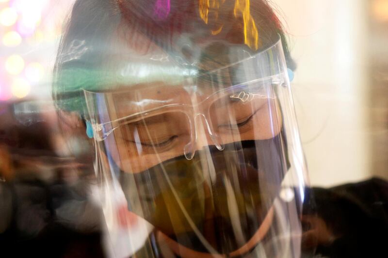 A cashier wears a face shield behind plastic protection as she works in a supermarket in Bangkok, Thailand. Reuters