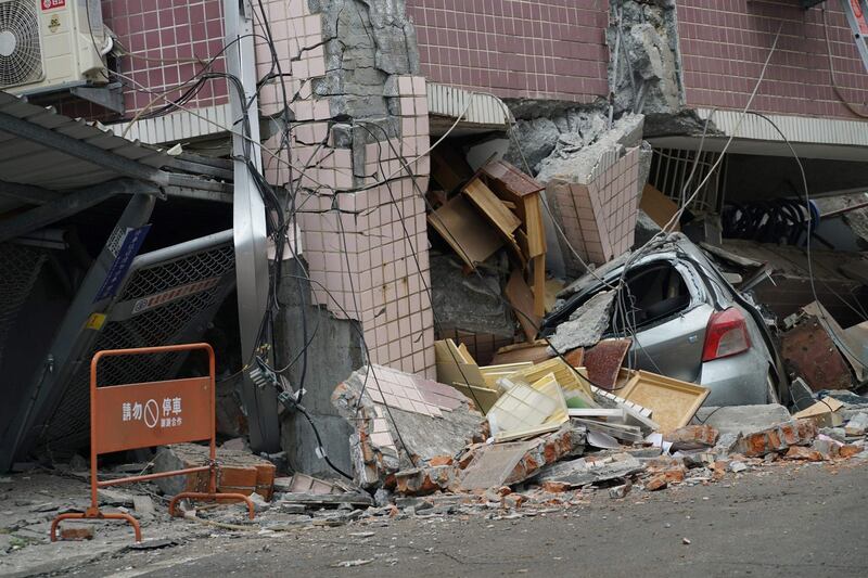 A car sits crushed by a building which came off its foundation after a 6.4 magnitude quake hit the eastern Taiwanese city of Hualien. Paul Yang / AFP
