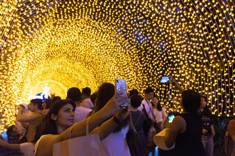 Visitors pose for a photos with a light installation, part of Christmas festivities at Gardens By The Bay in Singapore. Getty Images