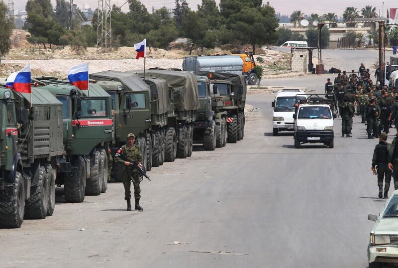 Syrian and Russian soldiers wait at the entrance of the Wafideen Camp for the arrival of buses carrying Jaish al-Islam fighters and their family members evacuated from the Eastern Ghouta town of Douma, on April 12, 2018. 
Rebels in Syria's Eastern Ghouta surrendered their heavy weapons and their leader left the enclave, a monitor said, signalling the end of one of the bloodiest assaults of Syria's seven-year war. / AFP PHOTO / Youssef KARWASHAN