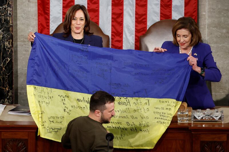 Ukrainian President Volodymyr Zelenskyy presents a flag to Vice President Kamala Harris and House Speaker Nancy Pelosi. Reuters