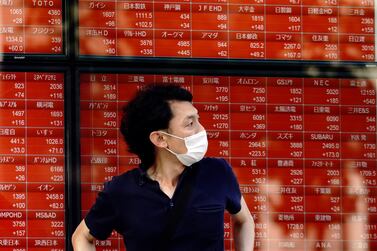 A man stands in front of an electronic stock board showing Japan's Nikkei 225 index at a securities firm in Tokyo. The recent surge in new cases, particularly in the US, highlights that volatility is set to stay in the markets, says Gaurav Kashyap. AP 