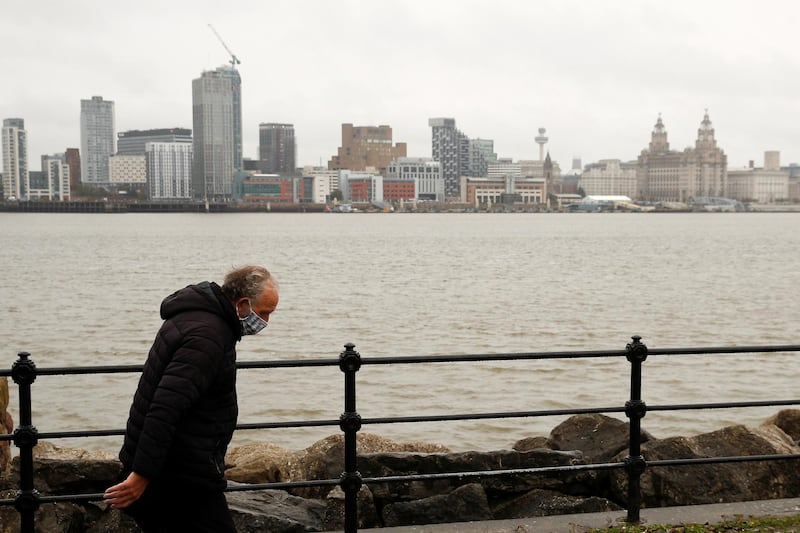 A man wearing a face mask walks along the River Mersey in Liverpool. Reuters