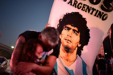 A father and daughter, fans of Diego Maradona, mourn as they gather by the Obelisk in Buenos Aires. AFP