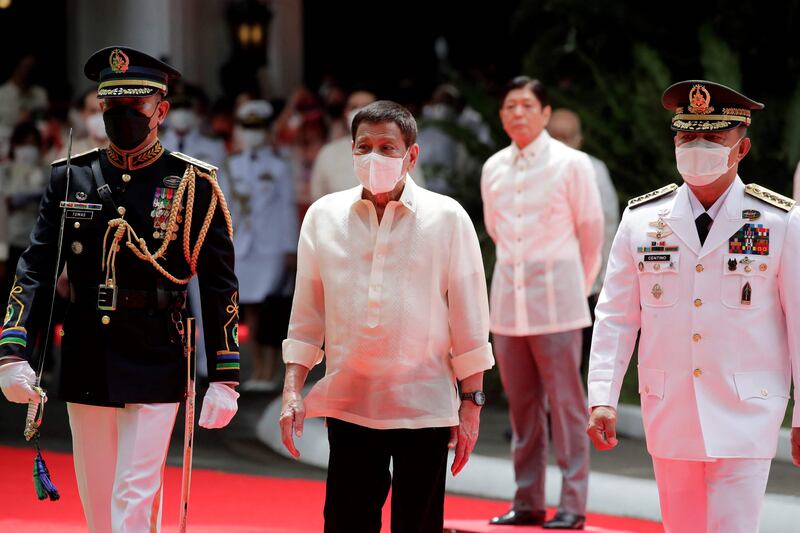 Departing Philippine President Rodrigo Duterte, centre left, is escorted as he reviews an honour guard, as incoming President Ferdinand Marcos J looks on, during the inauguration ceremony for Mr Marcos Jr, in Manila. AFP