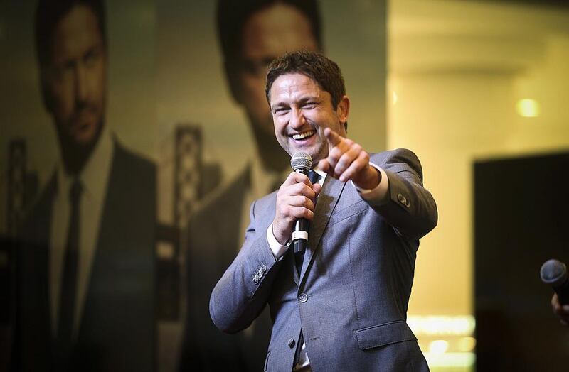 Scots actor Gerard Butler has a joke with a fan who holds aloft a Saltire, the Scottish flag, during his appearance at Dubai Mall on Friday night. Lee Hoagland / The National 