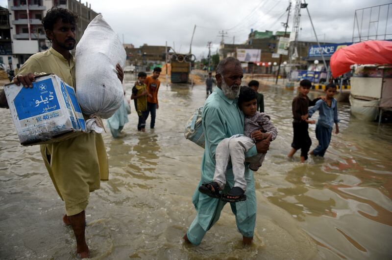 People wade through a flooded street after a rainstorm. AFP