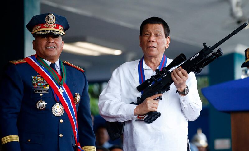 FILE - In this April 19, 2018 file photo, Philippine President Rodrigo Duterte, right, jokes to photographers as he holds an Israeli-made Galil rifle which was presented to him by former Philippine National Police Chief Director General Ronald "Bato" Dela Rosa at the turnover-of-command ceremony at the Camp Crame in Quezon city northeast of Manila. The first-ever visit to Israel of a leader of the Philippines is sure to be touted by Prime Minister Benjamin Netanyahu as another stirring success in his campaign to reverse years of isolation and enhance Israel's relations with various countries across the globe. (AP Photo/Bullit Marquez, File)