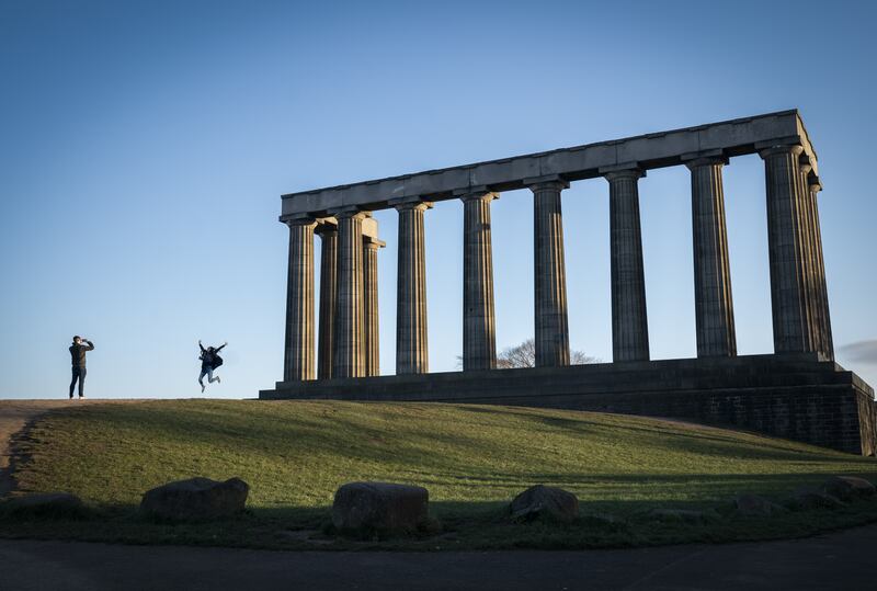 A couple take photographs alongside the National Monument on Calton Hill, Edinburgh, on Wednesday. PA