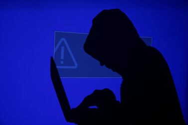 A hooded man holds a laptop computer as blue screen with an exclamation mark is projected on him in this illustration picture taken on May 13, 2017. REUTERS