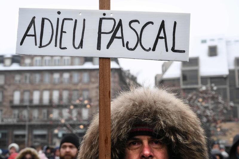 A man holds a placard reading "Goodbye Pascal". AFP