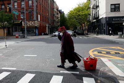 epa08412506 An elderly woman holds her hat as she wears a full face mask while crossing the street on the Lower East Side of New York, USA, 09 May 2020. New York City remains the epicenter of the coronavirus outbreak in the USA.  EPA/JASON SZENES