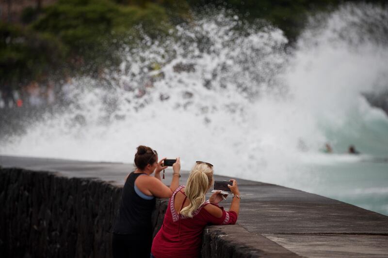 Visitors take photos of the waves crashing on the seawall. Bruce Omori / EPA
