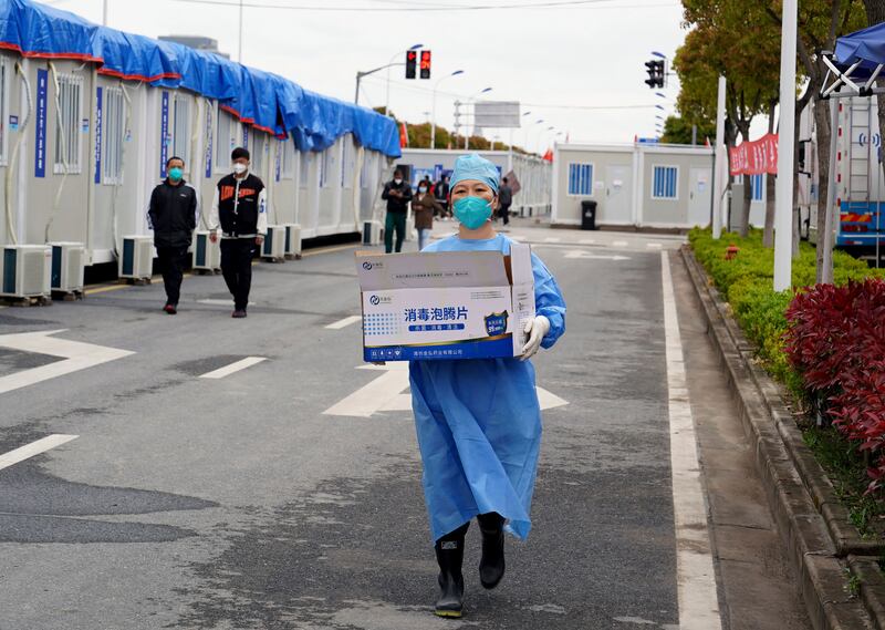 A woman carries a box of supplies at a makeshift hospital in Shanghai. AP