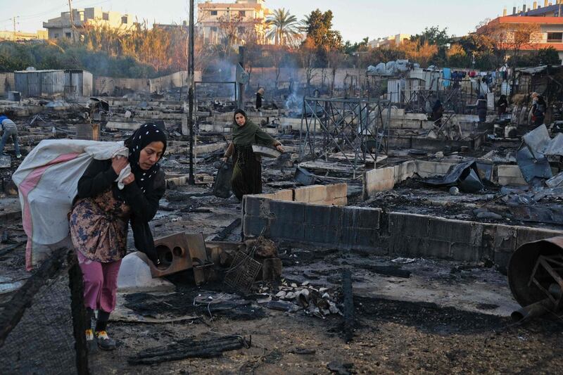 Syrian refugees salvage belongings from the wreckage of their shelters at a camp set on fire overnight in the northern Lebanese town of Bhanine. AFP