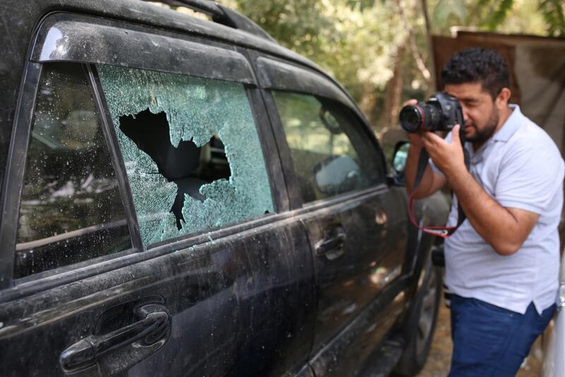 A photographer at work next to a damaged car in the aftermath of a rocket attack in central Kabul, Afghanistan.  EPA