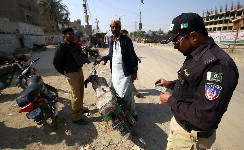 Pakistani security officials check identity cards at a roadside check point in Karachi. EPA
