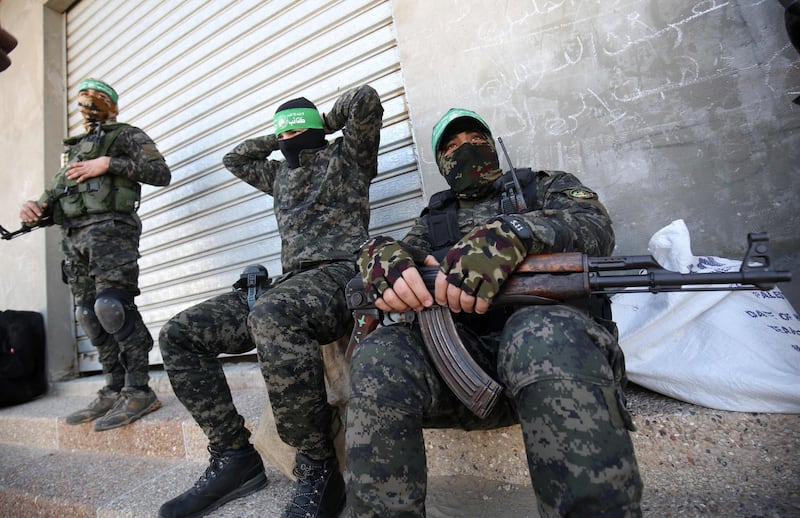 Palestinian fighters with Ezz-Al Din Al-Qassam Brigades, the armed wing of the Hamas movement, rest on a sidewalk during a patrol in Khan Yunis in the southern Gaza Strip on January 26, 2020.  / AFP / SAID KHATIB
