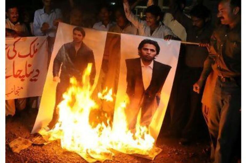 Angry Pakistani fans burn posters of Salman Butt, left, and Mohammad Asif in Multan.