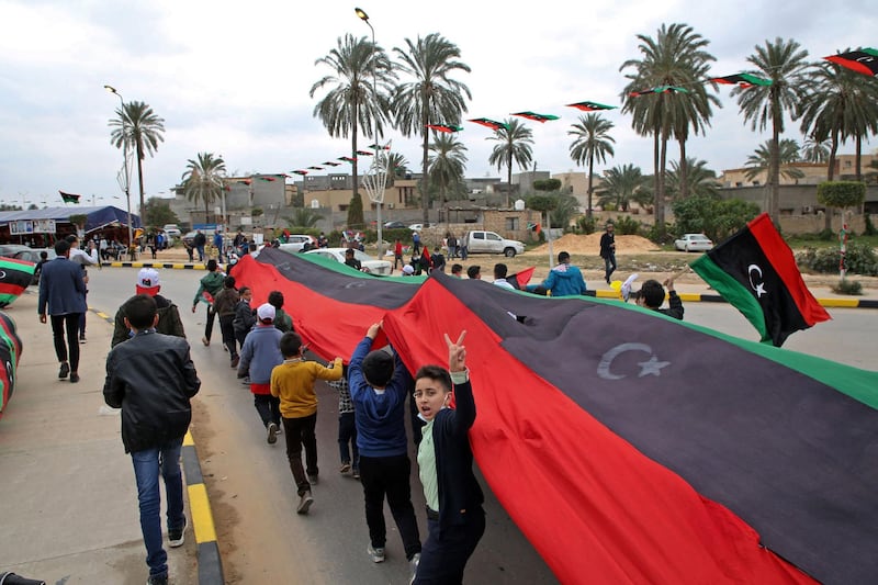 Children carry a Libyan flag as the country marks the 10th anniversary of the uprising that toppled Qaddafi in 2011. AFP