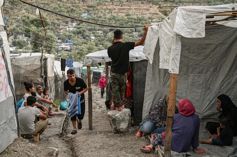 Refugees and migrants are pictured in a improvised tents camp near the refugee camp of Moria in the island of Lesbos on June 21, 2020. - Greece's announcement that it was extending the coronavirus lockdown at its migrant camps until July 5, cancelling plans to lift the measures on June 22, coincided with World Refugee Day on June 27, 2020. (Photo by ARIS MESSINIS / AFP)