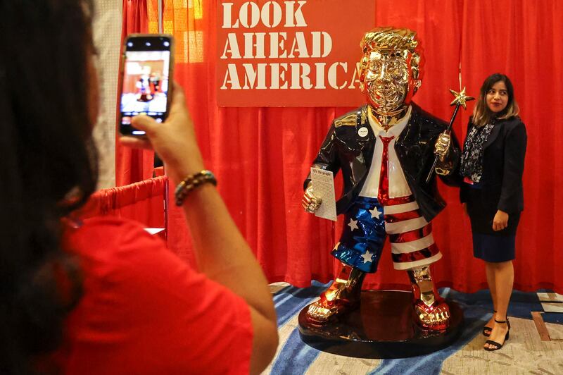 A woman poses for a photo with the golden Donald Trump statue at the Conservative Political Action Conference. AP Photo