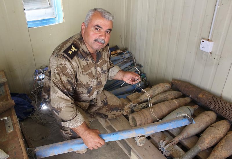 Lt Colonel Najmaldin next to defused mortar rounds turned into IEDs by ISIL. He holds a pressure activated detonator. Florian Neuhof for The National