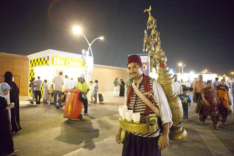 A traditional tea-pourer waits for customers as visitors thronged Global Village for the first day of Eid Al Adha. Razan Alzayani / The National