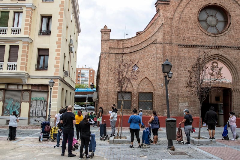 People queue to receive food at San Ramon Nonato Catholic parish in Puente de Vallecas district in Madrid, Spain. AP